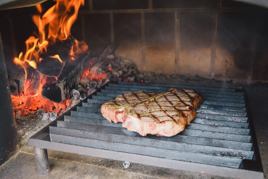 steak being grilled in an outdoor brick oven